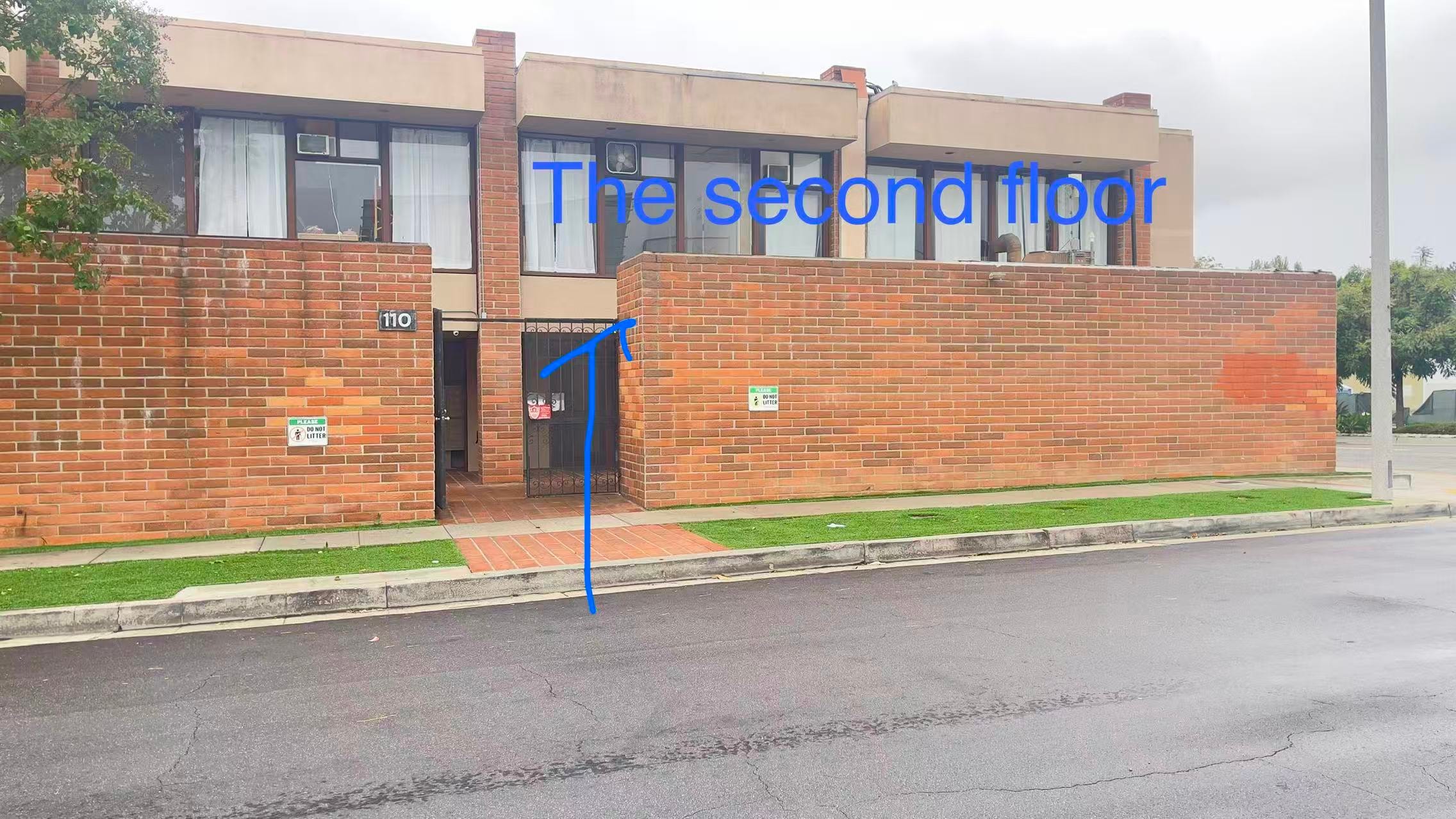 Street-level view of the 110 building entrance with an arrow pointing to the second-floor studio entrance