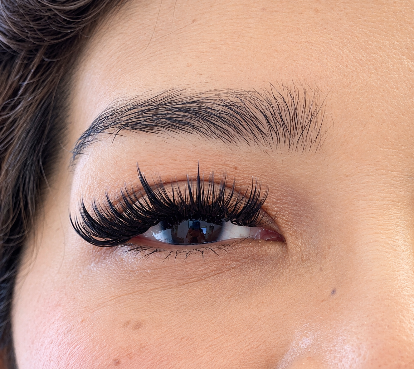 Macro view of wispy volume eyelash extensions and a groomed brow