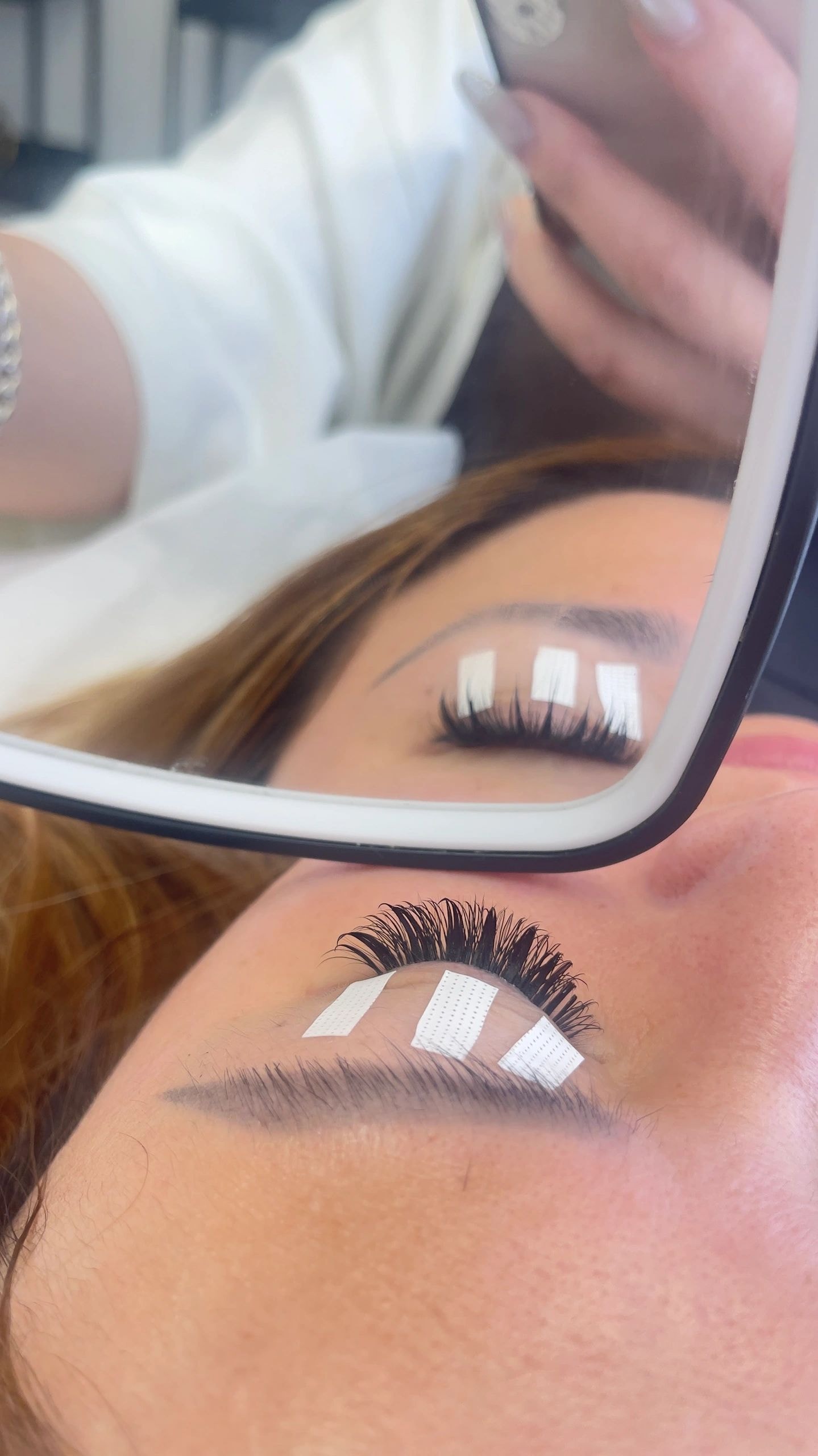 Client admiring her new lash extensions in a handheld mirror