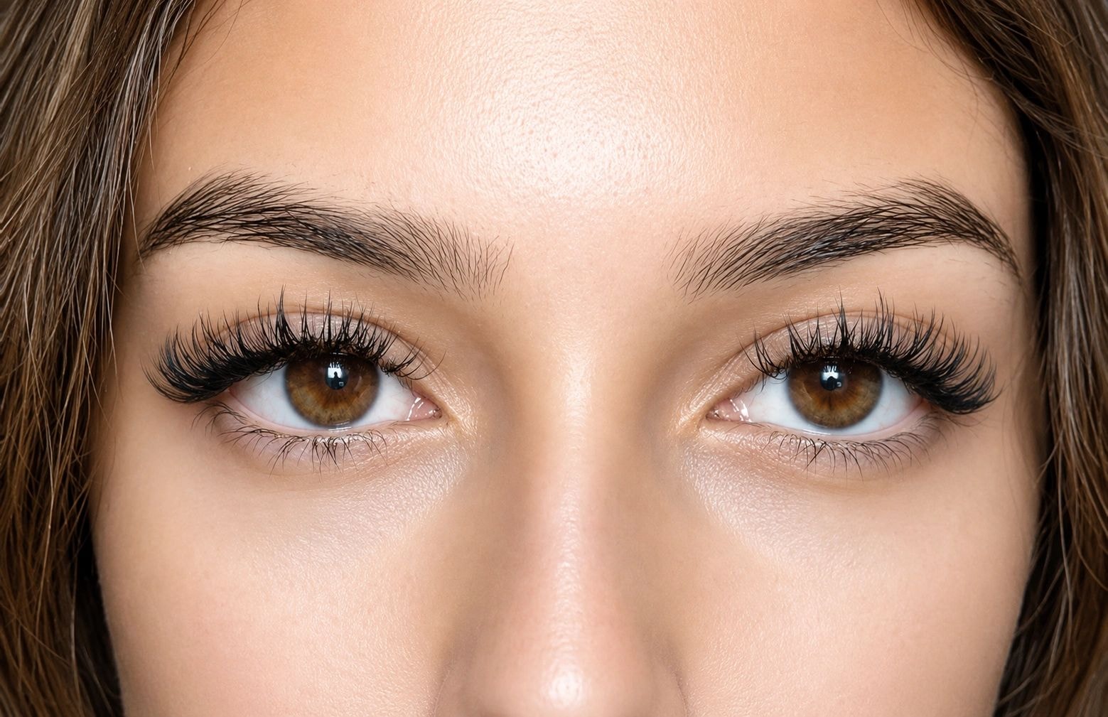 Both eyes framed by voluminous lash extensions in soft studio lighting